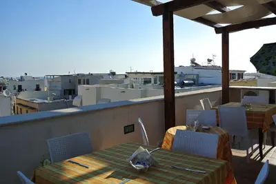 a patio with a table and chairs on a balcony at Hotel Il Melograno in San Vito lo Capo