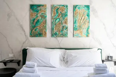 a bedroom with three paintings on the wall above a bed at Marmur Suite in Palermo