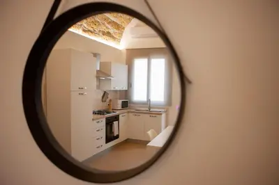 a kitchen with white cabinets and a mirror at Agorà Home in Terrasini