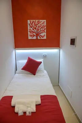a bed with red and white sheets and a red pillow at Corallo Rosso B&B in Terrasini