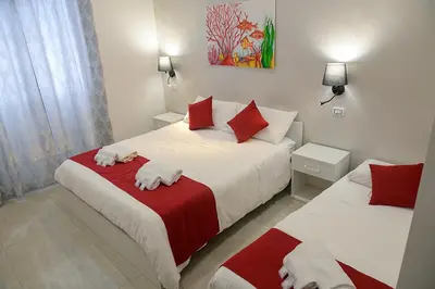 a bedroom with two beds with red and white sheets at Corallo Rosso B&B in Terrasini