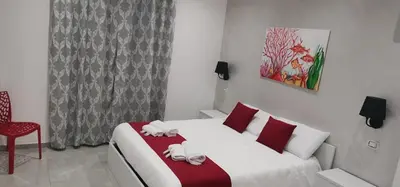 a bedroom with a bed and a red chair at Corallo Rosso B&B in Terrasini
