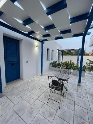 a patio with a table and chairs and a blue ceiling at B&B Santorini in Cinisi