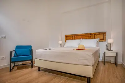 a bedroom with a bed and a blue chair at Suite Altamarea 