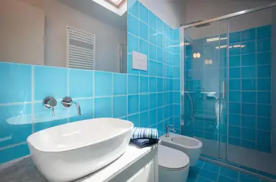 a blue tiled bathroom with a sink and a toilet at Kalsa Skyhome in Palermo