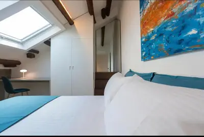 a bedroom with a white bed and a painting on the wall at Kalsa Skyhome in Palermo