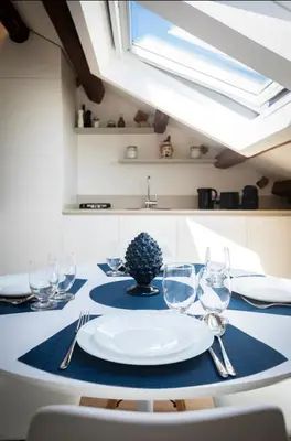a table with a white plate and glasses on it at Kalsa Skyhome in Palermo
