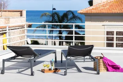 a patio with two chairs and a table and the ocean at Cube 67 - Terrace in Palermo
