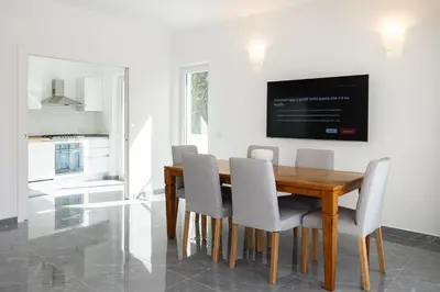 a dining room with a wooden table and white chairs at Cube 67 - Villa in Palermo