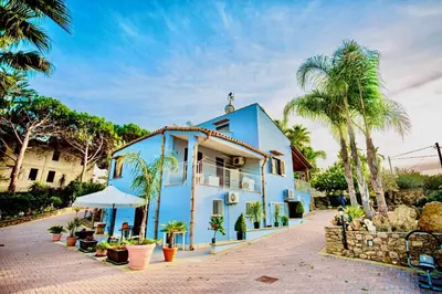 a blue house with palm trees in front of it at Villa Dorotea con piscina in Trappeto