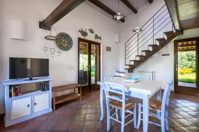 a dining room with a table and a tv at Villetta Rosamarina by Wonderful Italy in Cefalù