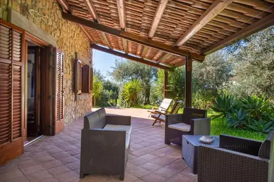 a patio with chairs and tables and a wooden pergola at Villetta Rosamarina by Wonderful Italy in Cefalù