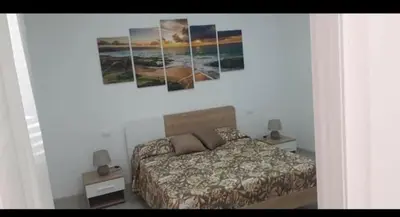 a bedroom with a bed and paintings on the wall at A Casa Ri Angela in San Vito lo Capo