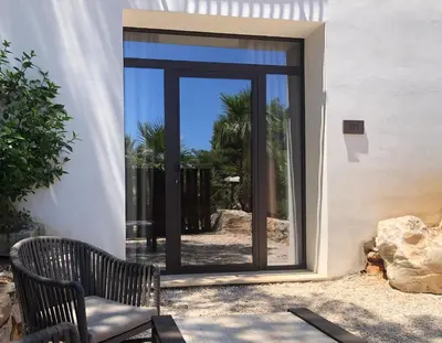 a glass door with a chair in front of a building at Araja Villa&Suite by Geocharme in San Vito lo Capo