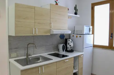 a small kitchen with a sink and a refrigerator at La terra del sole in Cinisi