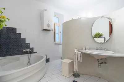 a bathroom with a tub and a sink and a mirror at Palazzo Damiani Apartment by DomuSicily in Palermo