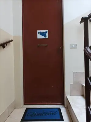 a brown door with a welcome mat in front of it at Amuri Siculo, Casa Vacanze Palermo centro in Palermo