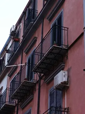 a red building with balconies and an air conditioner at Amuri Siculo, Casa Vacanze Palermo centro in Palermo