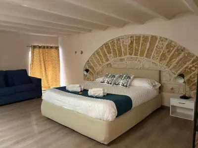 a bedroom with a large bed and a blue couch at Palermo alla Gancia Room in Palermo