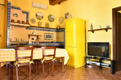 a kitchen with a table with chairs and a television at Villa Caterina in Torretta