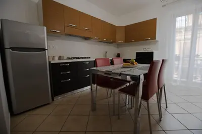 a kitchen with a table with chairs and a refrigerator at Cassaro Casa Vacanze in Castellammare del Golfo