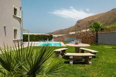 a backyard with a table and benches and a pool at Nuova Villa a Scopello con piscina privata in Balata di Baida