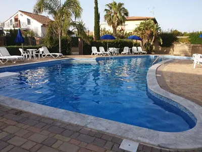 a large swimming pool with chairs and umbrellas at Mansarda Marina in Campofelice di Roccella