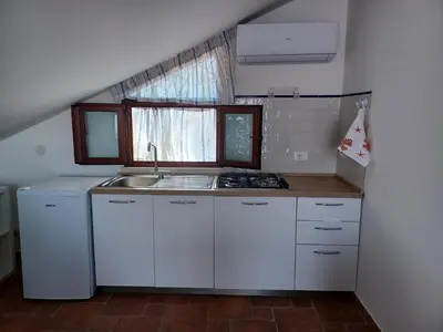 a kitchen with white cabinets and a sink and a window at Mansarda Marina in Campofelice di Roccella