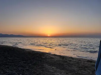 a sunset on the beach with the ocean at Mansarda Marina in Campofelice di Roccella