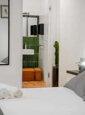 a bedroom with a white bed and a green tiled bathroom at Civico64 apartments in Castellammare del Golfo