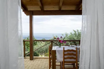 a table with a view of the ocean from a porch at VILLA BIFAMILIARE SCOPELLO in Scopello