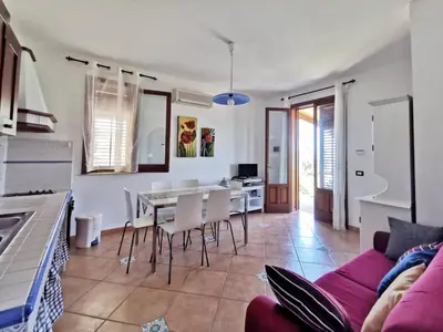 a living room with a purple couch and a table and chairs at VILLA BIFAMILIARE SCOPELLO in Scopello