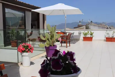 a patio with flowers and an umbrella on a roof at Attico in centro città in Alcamo