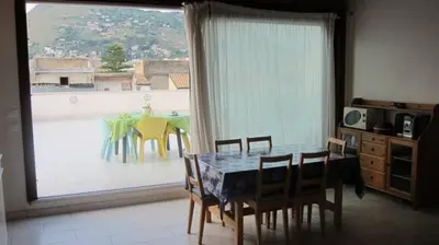 a dining room with a table and chairs and a large window at Attico in centro città in Alcamo