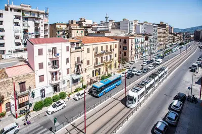 a city with a train on a street with cars at CENTRAL STATION APARTMENTS - Fanale Rentals in Palermo