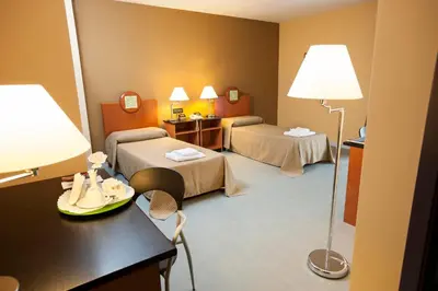 a room with two beds and a table with a lamp at Albergo Athenaeum in Palermo
