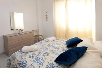 a bedroom with a bed with blue and white pillows at Confortevole appartamentino in Castellammare del Golfo