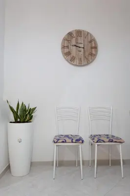 two chairs and a clock on a wall at Confortevole appartamentino in Castellammare del Golfo