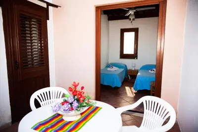 a room with two chairs and a table with flowers on it at Case Vacanza Sabbia Rosa in San Vito lo Capo