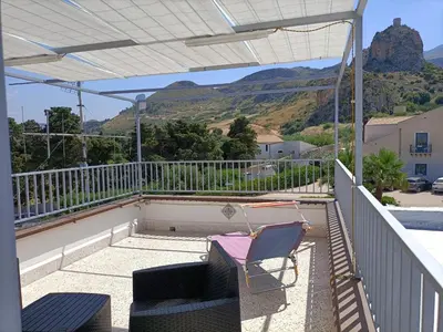 a balcony with a table and chairs and mountains at La casetta a Scopello in Scopello