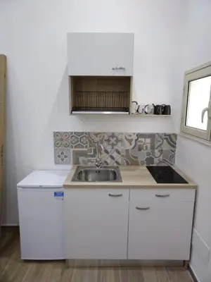 a kitchen with white cabinets and a sink at IGIEA ROOMS in Palermo