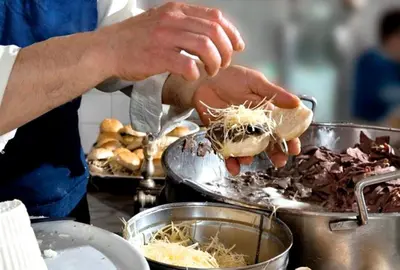 a person is preparing food in a pan at IGIEA ROOMS in Palermo