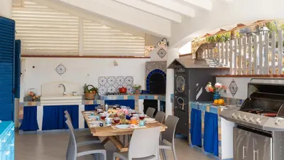 a kitchen with blue cabinets and a table with food on it at VILLA OLIMPIA 6&2, Emma Villas in Castellammare del Golfo