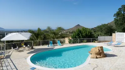 a large swimming pool with chairs and an umbrella at VILLA OLIMPIA 6&2, Emma Villas in Castellammare del Golfo
