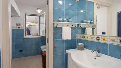 a blue tiled bathroom with a sink and a toilet at VILLA OLIMPIA 6&2, Emma Villas in Castellammare del Golfo