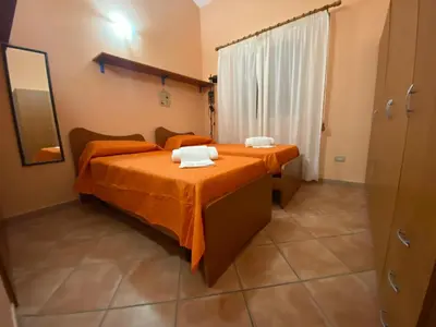 two beds in a room with orange sheets at Villa in recidence a 100 metri dal mare con servizio di piscina a 100 metri vicino Cefalu in Campofelice di Roccella