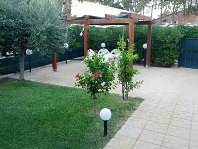 a garden with a pavilion and a tree with flowers at Villa in recidence a 100 metri dal mare con servizio di piscina a 100 metri vicino Cefalu in Campofelice di Roccella