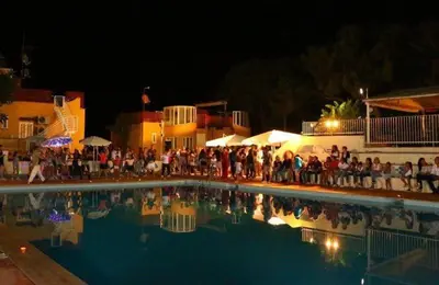 a group of people sitting around a swimming pool at night at Appartamento Ashur Mondello in Palermo