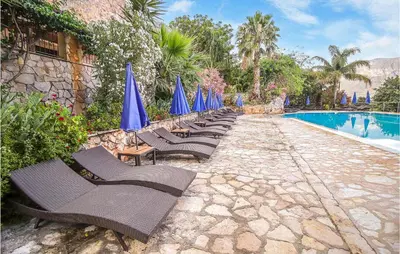 a row of chairs with blue umbrellas next to a swimming pool at Pietro 4 in San Vito lo Capo