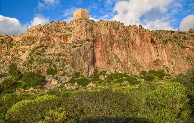 a rocky mountain with a tower on top of it at Pietro 4 in San Vito lo Capo